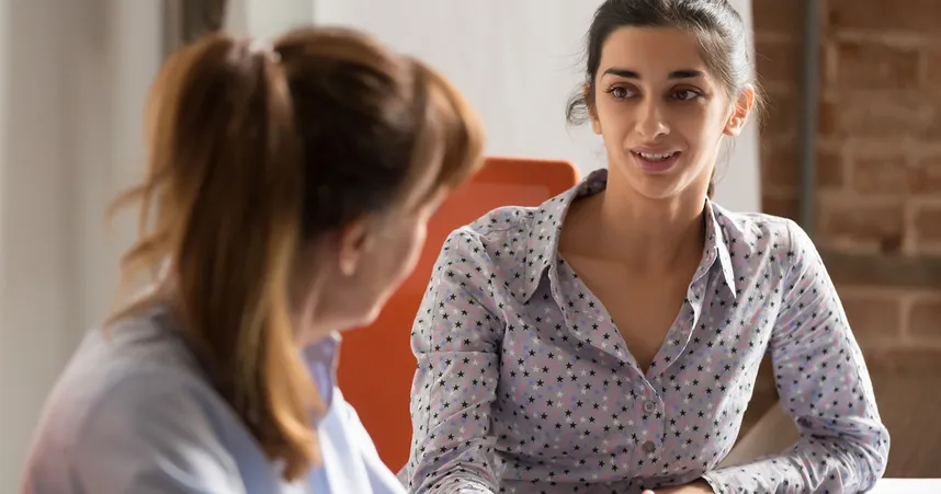 Two women sit down for a conversation in an office
