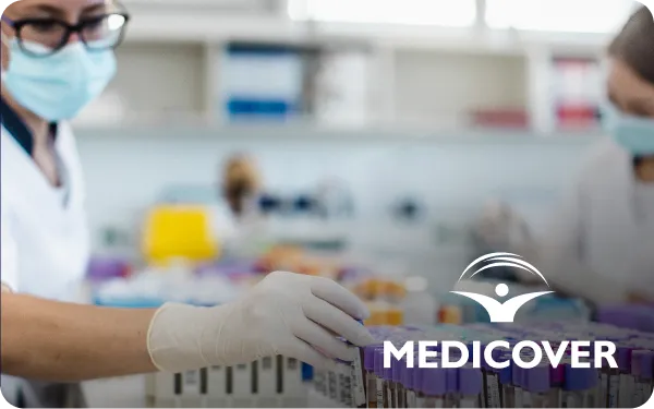 Lab technicians wearing masks and gloves work with test tubes in a medical laboratory. Medicover logo is visible.