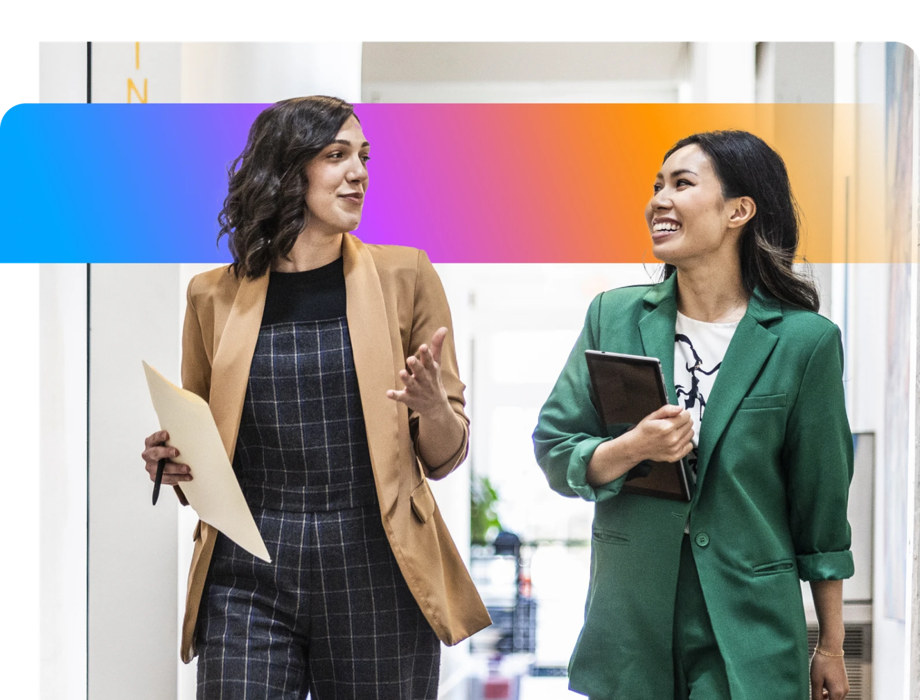 Two women in business attire walking and talking in a hallway, holding documents, with a colorful gradient overlay above them.