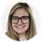 Headshot of a women with dark glasses. She is smiling into the camera.