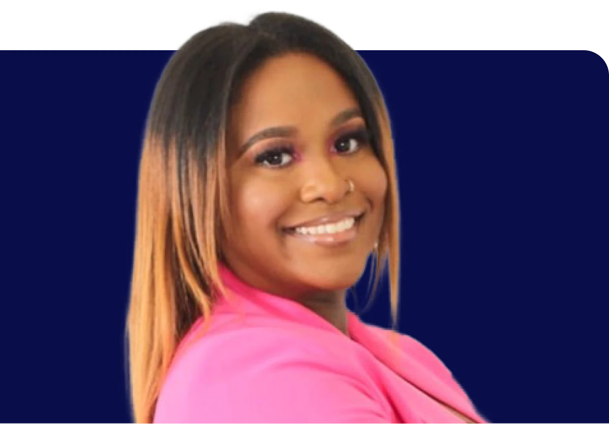 Smiling person with long hair wearing a bright pink blazer against a dark blue background.