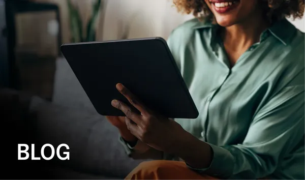 Smiling person in a green shirt holds a tablet while sitting on a couch. The word "BLOG" is in the lower left corner.