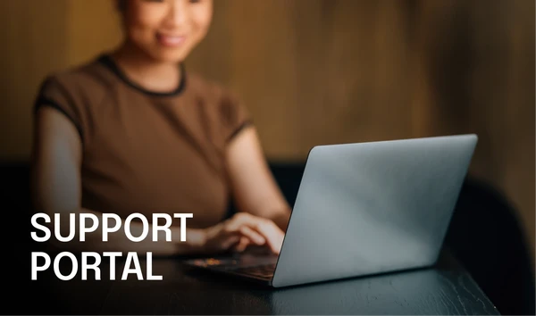 Woman using a laptop with the text "Support Portal" on the left. The background is softly blurred, emphasizing the focus on the laptop.