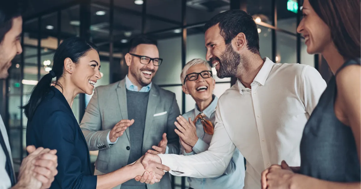 Dieses Bild zum Blogartikel Was macht interne Kommunikation unverzichtbar für unternehmerischen Erfolg zeigt Kolleg*innen, die sich gegenseitig zu einem Erfolg beglückwünschen.