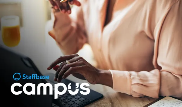 Person typing on a laptop with a notepad nearby. The text "Staffbase Campus" is visible in the foreground.