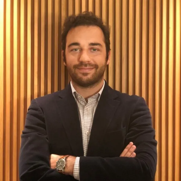 A photo of Gonzalo Rojo smiling with arms crossed, while wearing a business suit.