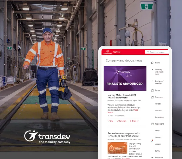 Man in safety gear walking in a depot; Transdev logo and company news displayed on a digital screen.