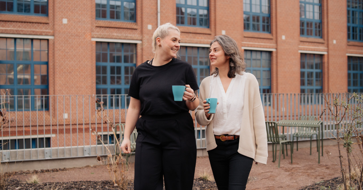 two women walking with coffee cups
