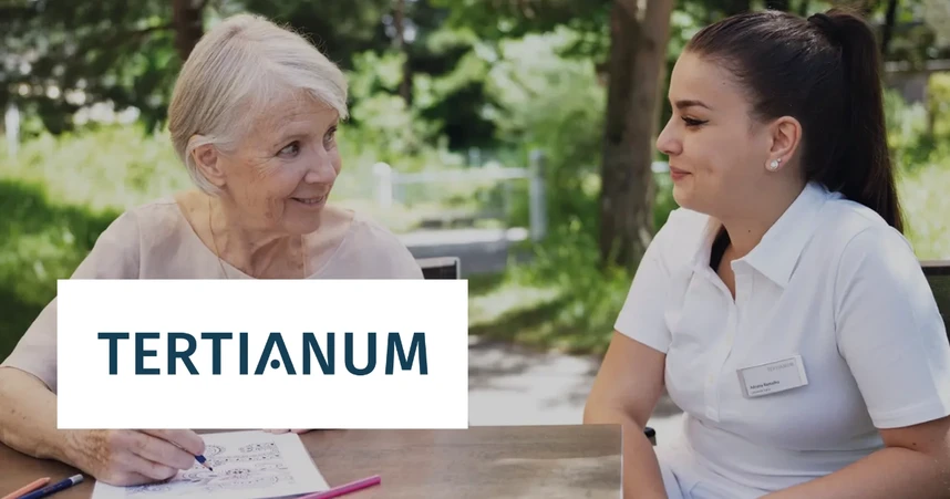 Elderly woman and caregiver sitting outdoors, smiling and talking. The caregiver is in a white uniform. Tertianum logo is visible.