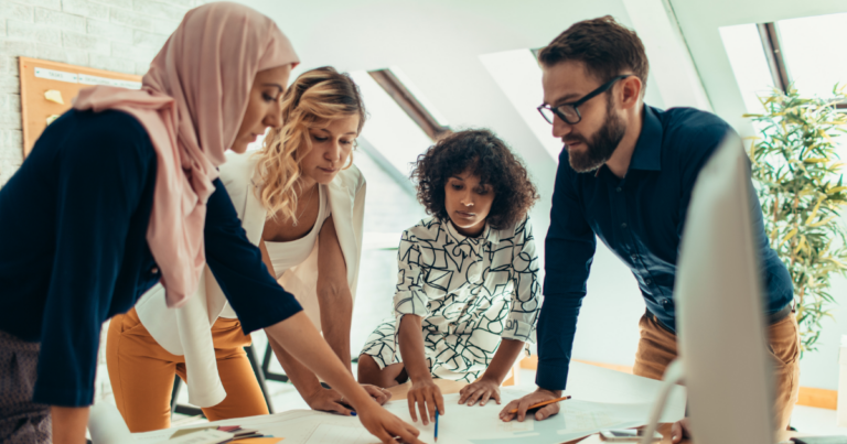 image of four coworkers working on something on a table