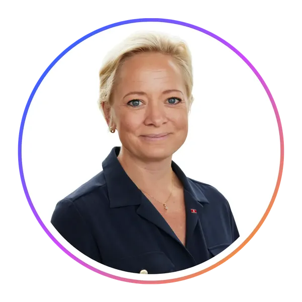 Smiling person with short blonde hair wearing a navy blouse, inside a circular frame with a colorful border on a white background.