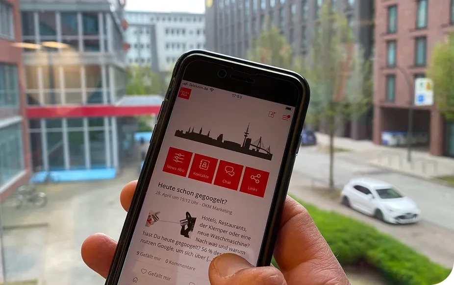 Hand holding a smartphone displaying a news app, with a cityscape visible through a window in the background.